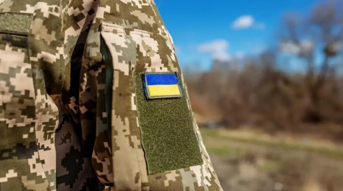 Рукав піксельної форми з нашивкою прапора України на тлі неба