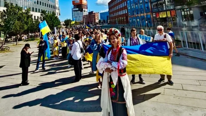 Люди держат большой украинский флаг на улице города во время празднования