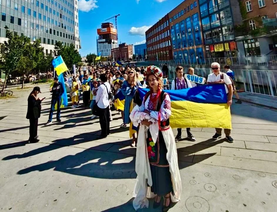 Люди держат большой украинский флаг на улице города во время празднования