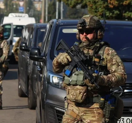 Військові в камуфляжі з автоматами біля сірого мікроавтобуса на вулиці