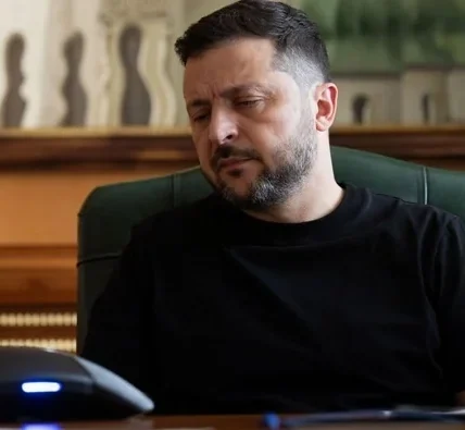Зеленський у чорній футболці сидить за столом у зеленому кріслі кабінету