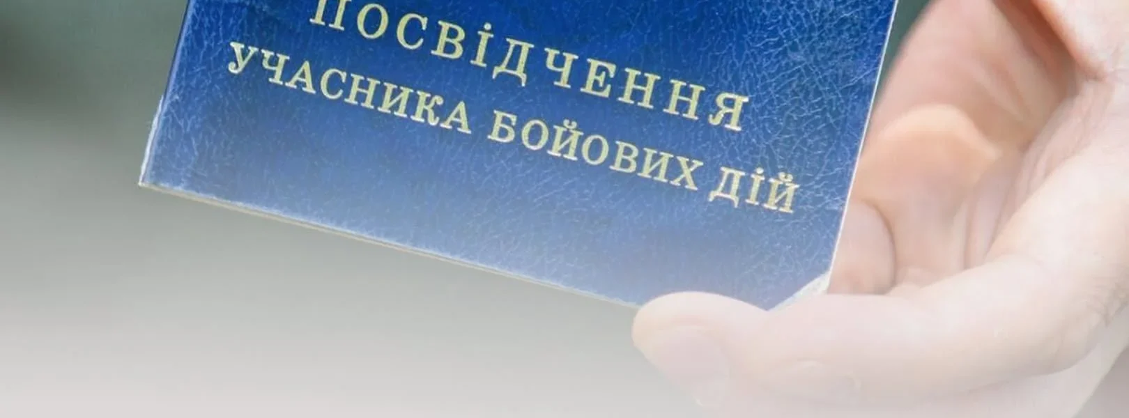 Рука тримає синє посвідчення учасника бойових дій України для його відновлення