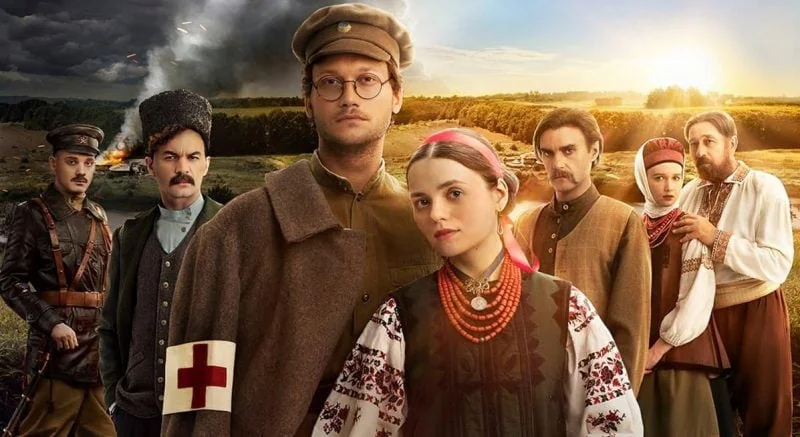 Група героїв історичної драми в традиційному вбранні та військовій формі на тлі поля з димом