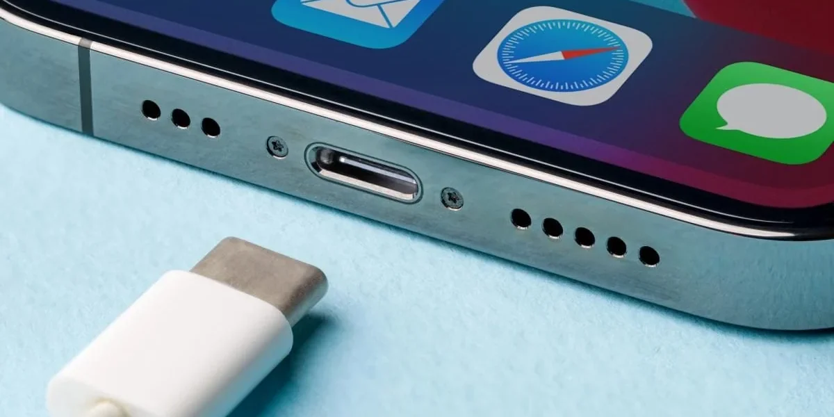 Нижня частина iPhone з портом USB-C і білим кабелем на блакитному тлі