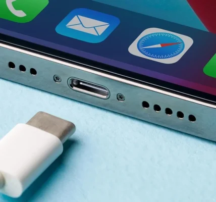 Нижня частина iPhone з портом USB-C і білим кабелем на блакитному тлі