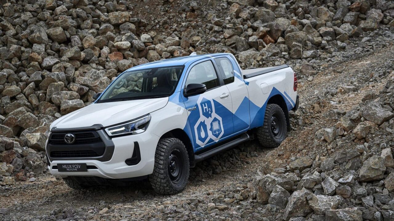 Білий та синій водневий пікап Toyota Hilux на кам'яному узбіччі