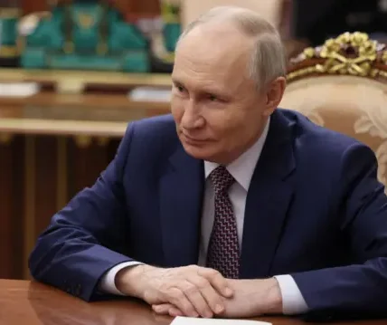 Володимир Путін у синьому костюмі сидить за столом у кабінеті