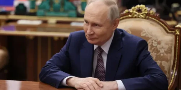 Володимир Путін у синьому костюмі сидить за столом у кабінеті